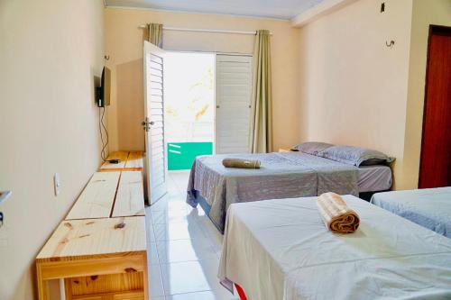 a bedroom with two beds and a door to a balcony at Residência Lençóis Pousada in Barreirinhas