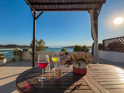 two glasses of wine sitting on a table on a patio at Sea Breeze - Home with a View in Bouzéïka