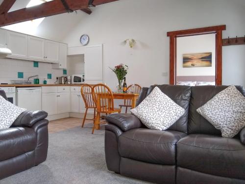 a living room with a leather couch and a table at Sparrow in Shipton Gorge