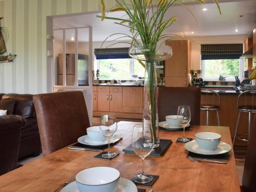 ein Esstisch mit Gläsern und einer Vase darauf in der Unterkunft Treetops in Bowness-on-Windermere