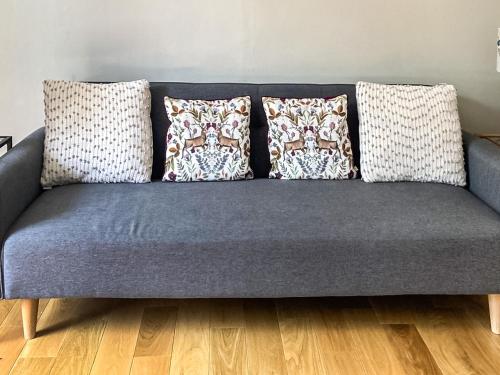 a blue couch with pillows on a wooden floor at Riverside Cottage in Blair Atholl