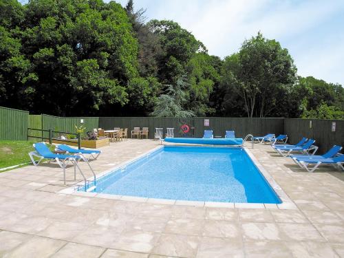a swimming pool with blue chairs at Discovery in Cheriton Bishop