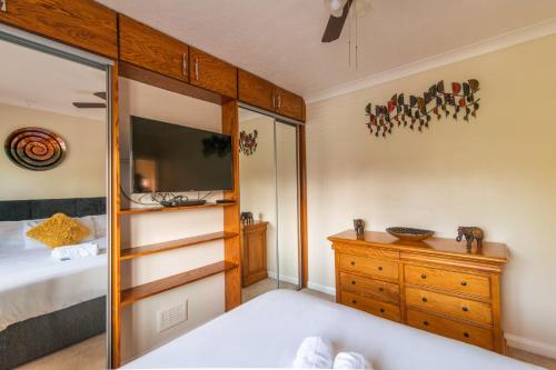 ein Schlafzimmer mit einem Bett, einer Kommode und einem TV in der Unterkunft Stylish 4-Bedroom Home with Modern Comforts in Derby