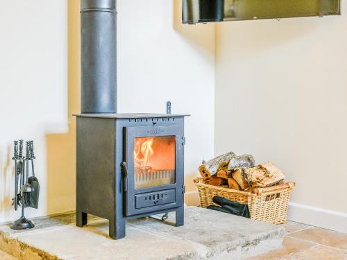 una estufa de leña en una habitación con una cesta de leña en Pipistrelle - Uk30758, en Bream