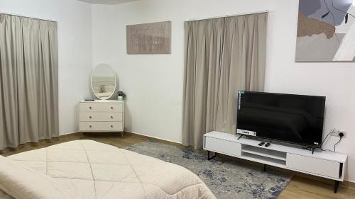 a bedroom with a flat screen tv on a dresser at المسارات الدولية in Mawāliḩ