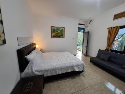 a bedroom with a bed and a couch at Hillside guest house and restaurant in Gitgit
