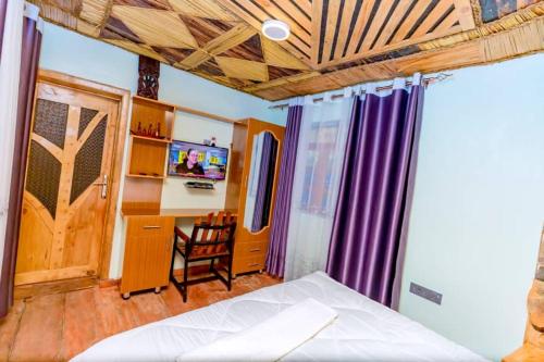 IKORO RESORT Musanze في روهينجيري: غرفة نوم بها سرير وسقف خشبي