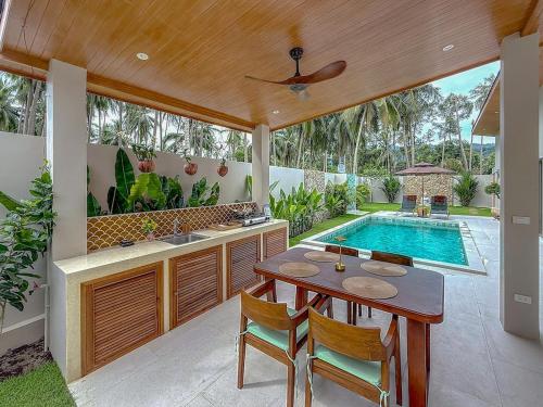 een keuken met een tafel en een zwembad bij Villa Souimanga 2Bed Balinese style Garden & Pool in Mae Nam