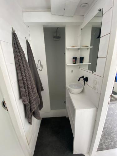 a white bathroom with a sink and a mirror at la cachette bas in Salies-de-Béarn
