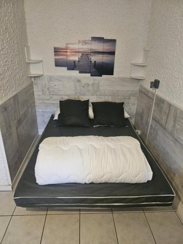 un grande letto con lenzuola bianche e cuscini neri di PALMA II a Port-la-Nouvelle