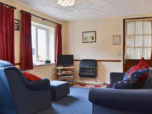 a living room with two chairs and a television at Wrens Nest in Llanfair Caereinion