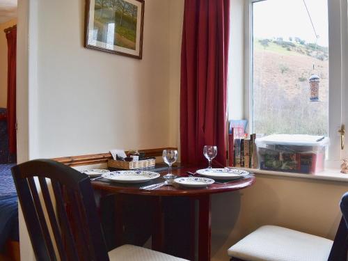 a table with two wine glasses and a window at Wrens Nest in Llanfair Caereinion