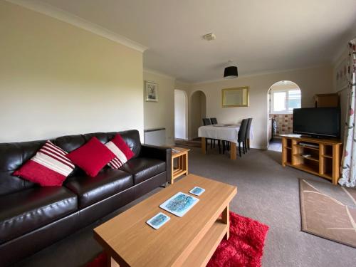 ein Wohnzimmer mit einer schwarzen Ledercouch und einem Tisch in der Unterkunft Tresco - B6520 in Saint Cleer