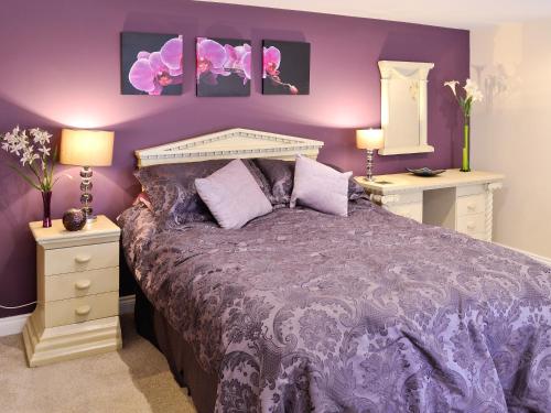 a purple bedroom with a bed and two night stands at Stable Cottage in Penrhyn Bay