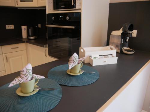 two cups and saucers on a kitchen counter at L'Enclos de La Grande Flûte 
