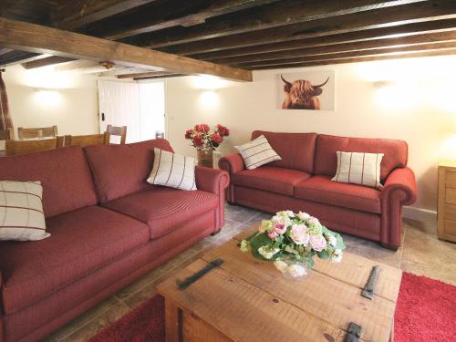 ein Wohnzimmer mit zwei roten Sofas und einem Tisch in der Unterkunft Granary Cottage - E5626 in Wainfleet All Saints
