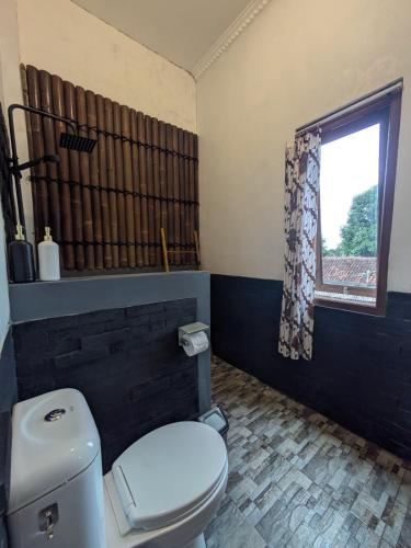 a bathroom with a white toilet and a window at ZEN MOON Hostel in Yogyakarta