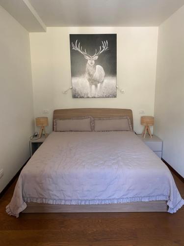 Un dormitorio con una cama con un cuadro de ciervo en la pared. en Maison Poluc - Cadeau des Alpes, en Champoluc