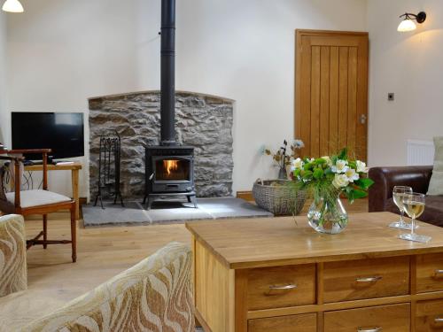 a living room with a fireplace and a table with flowers at Sgubor Ucha in Trefriw