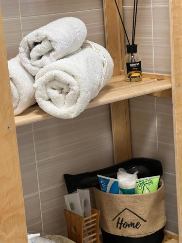 a bathroom with towels on a shelf with a trash can at Квартира в центре города in Astana