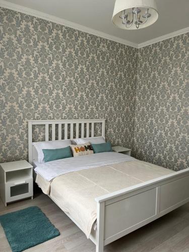 a bedroom with a bed and a wall with wallpaper at Квартира в центре города in Astana