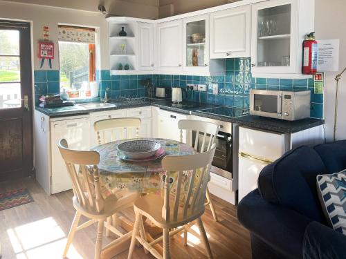 a kitchen with white cabinets and a table and chairs at Swan in Welney
