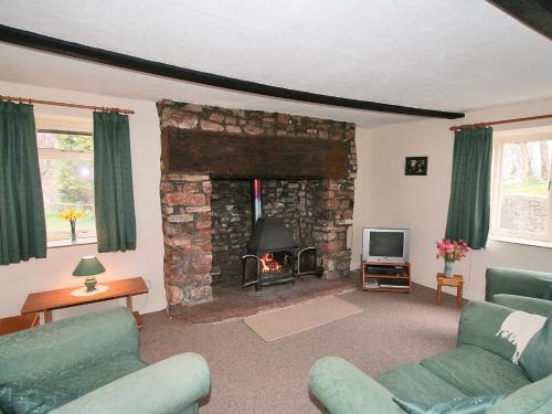ein Wohnzimmer mit einem Steinkamin und einem TV in der Unterkunft Maxmills Cottage - E1852 in Banwell