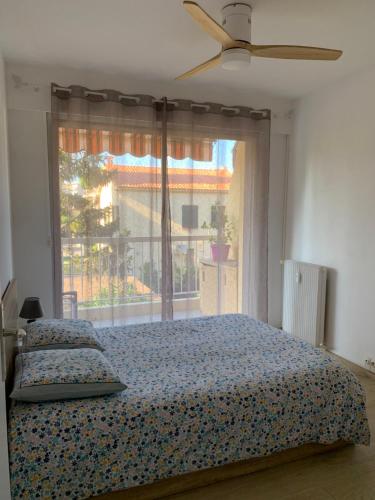 Un dormitorio con una cama y una ventana grande en Agréable 2 pièces à 150 m de la mer, en Cagnes-sur-Mer