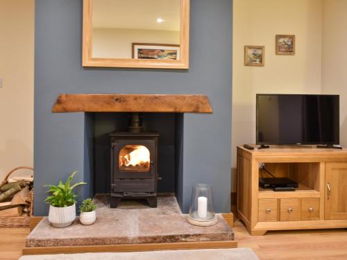 a living room with a fireplace and a tv at Pippa's Cottage - Uk42332 in Little Blencow