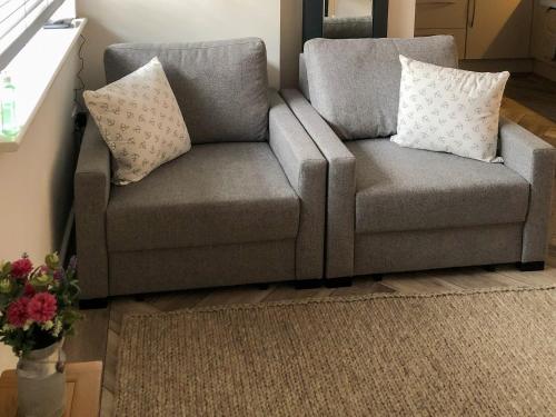 a gray couch with pillows on it in a living room at Whinacres Cottage 1894 in Conwy