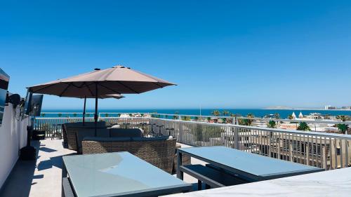 a patio with tables and an umbrella and the ocean at Hotel Cuatro Palmas in Puerto Peñasco