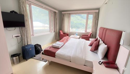 a bedroom with a bed and two chairs and a television at Hotel Sunrise Meadows Mountain in Manāli