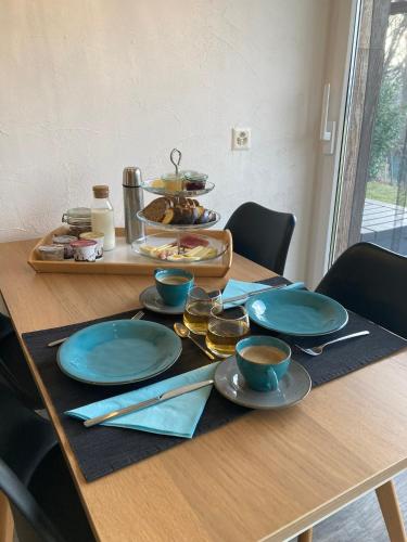 een houten tafel met blauwe platen en bekers erop bij Bnb Pavillon Paisible in Orsonnens