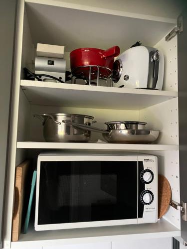 a microwave in a kitchen with pots and pans at Bnb Pavillon Paisible in Orsonnens