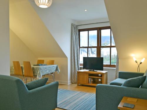 a living room with a television and a table with chairs at Herdwick Heights in Keswick