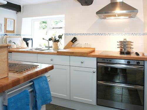 eine Küche mit weißen Schränken und einem Herd mit Backofen in der Unterkunft Blease Cottage in Threlkeld