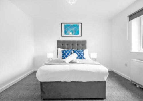 een witte slaapkamer met een groot bed met blauwe kussens bij Stylish 2 Bed Apartment - Smart TV - WiFi - Parking 27C in Sleightholme