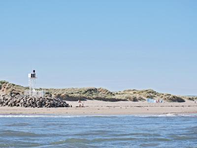 a beach with a lighthouse and people on the beach at Waters Edge in Instow