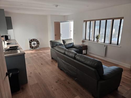 una sala de estar con un sofá de cuero negro y sillas en Little Fairacre - Two double bedroom annexe, en Braunton