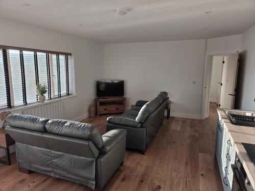 Sala de estar con 2 sofás de cuero y TV en Little Fairacre - Two double bedroom annexe, en Braunton