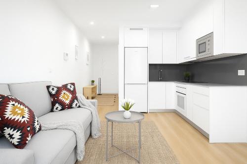 a white living room with a couch and a table at Apartamentos La Gringa Centro Gijon II Obra nueva con posibilidad de Parking in Gijón