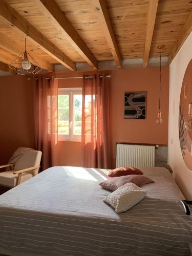 a bedroom with a large bed with a wooden ceiling at la bastilac chambre terracotta in Garganvillar