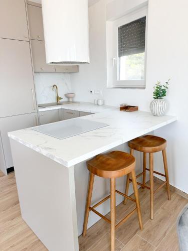 a kitchen with a white counter and two stools at Roza in Primošten