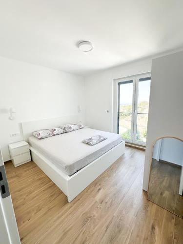 a white bedroom with a bed and a large window at Roza in Primošten