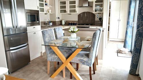 a kitchen with a glass table with chairs and a refrigerator at Luxury Lodge at Southview - perfect for couples with pond view and sun room in Skegness