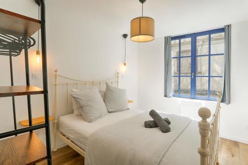 a bedroom with a white bed and a window at L'Escapade Médiévale Appartement neuf in Josselin