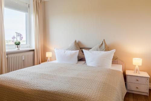 a bedroom with a bed with pillows and a window at Haus Uthlande Uthlande Whg 49 Inselauszeit in Wyk auf Föhr