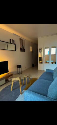 een woonkamer met een blauw bed en een televisie bij Suite vue sur la Tour Eiffel in Courbevoie