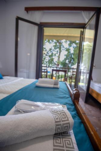 ein Schlafzimmer mit einem Bett mit blauer Bettwäsche und einem Fenster in der Unterkunft Afissos Blu Hotel in Áfissos