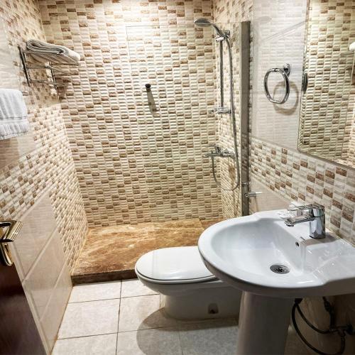 a bathroom with a shower and a toilet and a sink at بنان روز - شقق مخدومة in Hafr Al-Batin